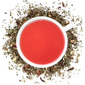 A white cup filled with Organic Sugar Crush Tea surrounded by the loose leaf blend.